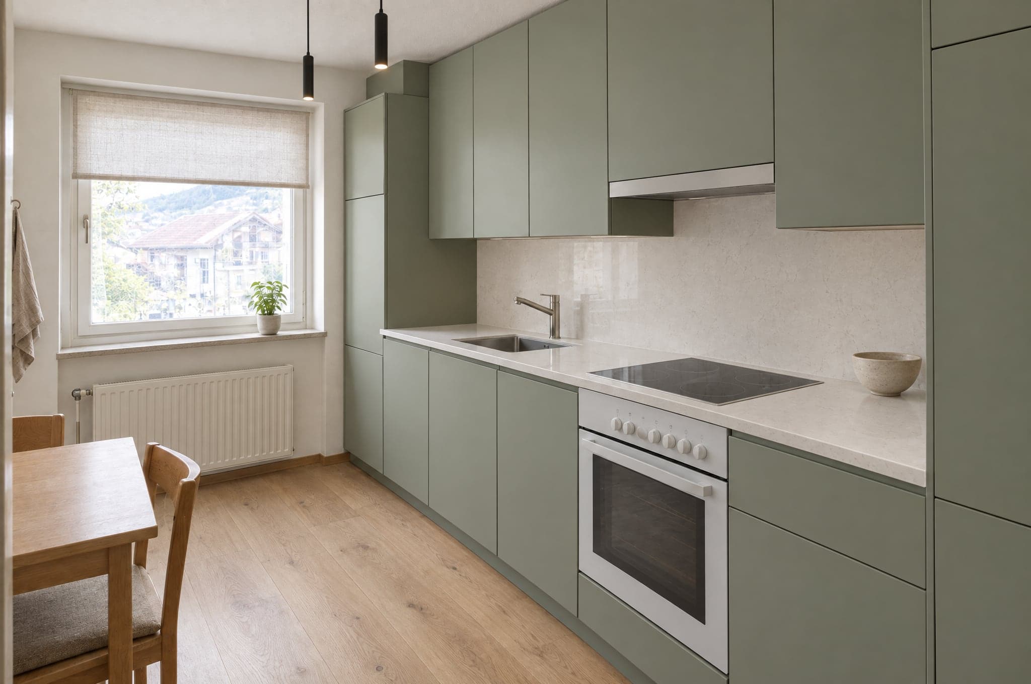 A dated oak kitchen rendered with matte sage fronts, a quartz worktop and oak flooring